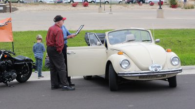 a couple guys looking at a VW Beetle