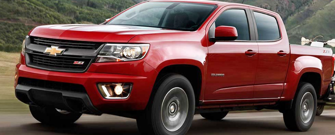 2015 Red Chevy Colorado pulling trailer in mountains